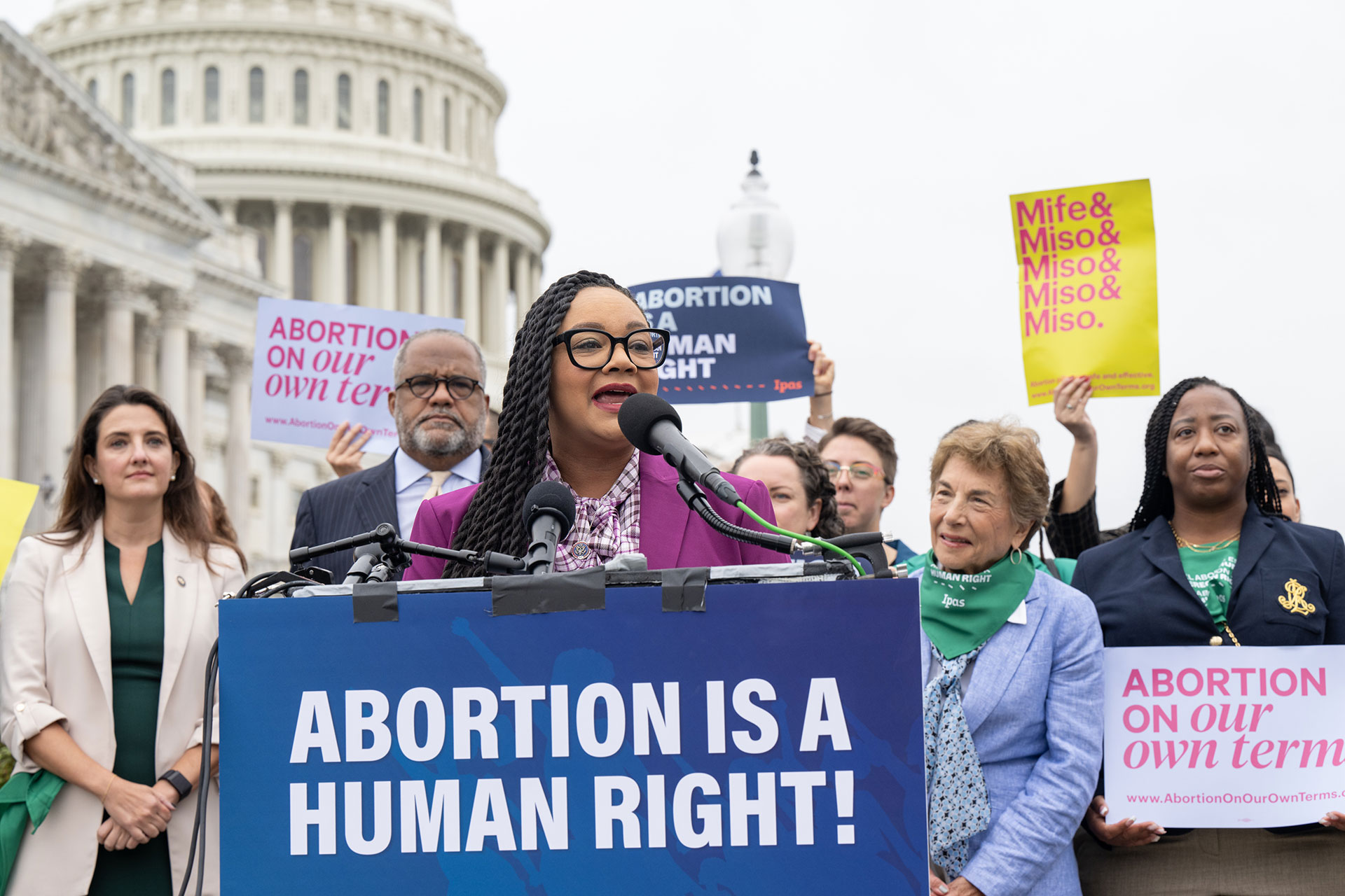 Representative Nikema Williams of Georgia, speaks at a press conference A group of people, including a woman speaking at a podium with a sign that reads "Abortion is a human right!" stand in front of the U.S. Capitol. Supporters hold signs advocating for abortion rights.